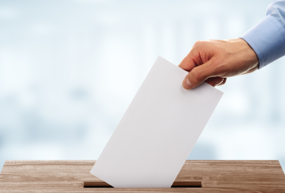 Un electeur vote en deposant leur voix dans une urne